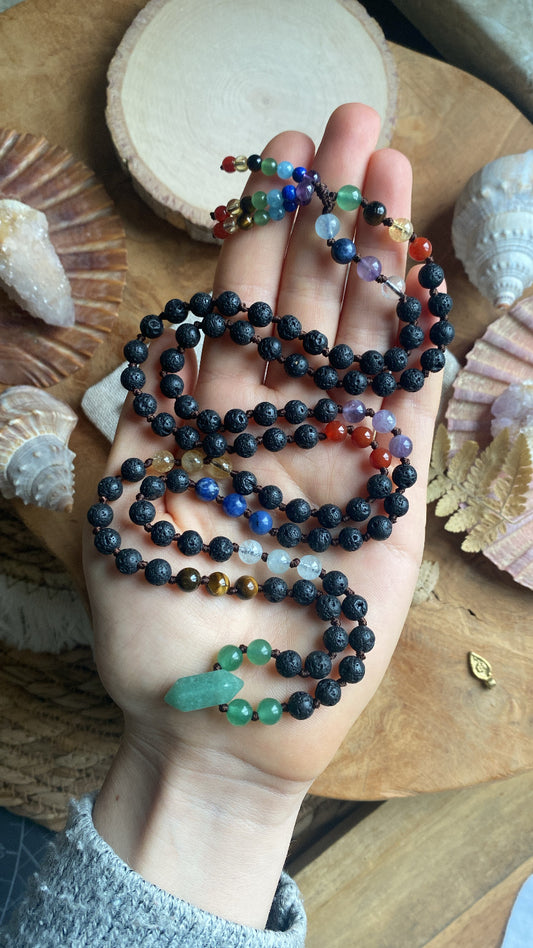 Chakra Mala Kette 108 Perlen Diese handgefertigte Mala Kette, die sieben Chakras harmonisieren will. Mit 108 Perlen aus Edelsteinen, darunter Aventurin als Anhänger. Jede Perle misst ca. 6 mm und wurde mit Liebe und Geduld in meditativer Arbeit geknüpft.