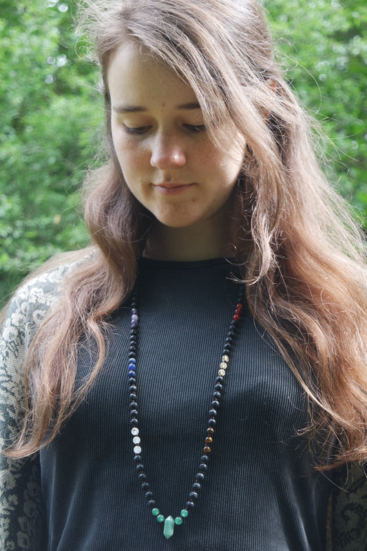 Chakra Mala Kette 108 Perlen Diese handgefertigte Mala Kette, die sieben Chakras harmonisieren will. Mit 108 Perlen aus Edelsteinen, darunter Aventurin als Anhänger. Jede Perle misst ca. 6 mm und wurde mit Liebe und Geduld in meditativer Arbeit geknüpft.