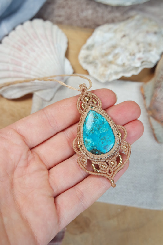 Handgeknüpfte Makramee Kette Strandseele mit blauem Chrysokoll und Messingperlen in sandfarbenem Makramee auf einer Hand liegend.