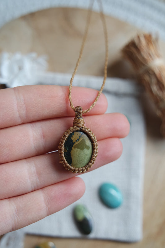 Handgemachte Makramee-Kette ‚Himmelssand‘ mit ovalem Türkisstein – fotografiert auf Leinentuch mit dekorativen Steinen