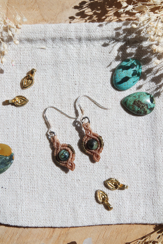 Nahaufnahme der handgeknüpften Ohrringe ‚Lichtkuss‘ – rund geschliffene Türkisperlen in zartem Makramee eingefasst