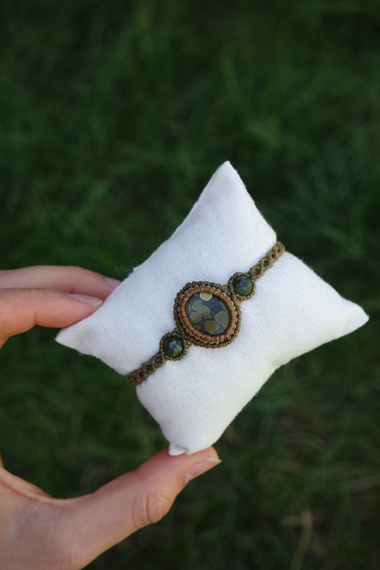 Detailaufnahme des Armbands ‚Lichtbrunnen‘ – ovaler Naturstein mit goldgrüner Maserung, eingerahmt von olivbraunem Garn