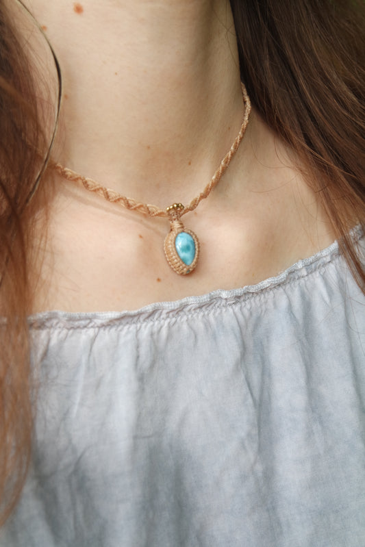 Makramee-Kette mit verstellbarem Schiebeknoten, Larimar und Messingperlen auf Holzunterlage.
