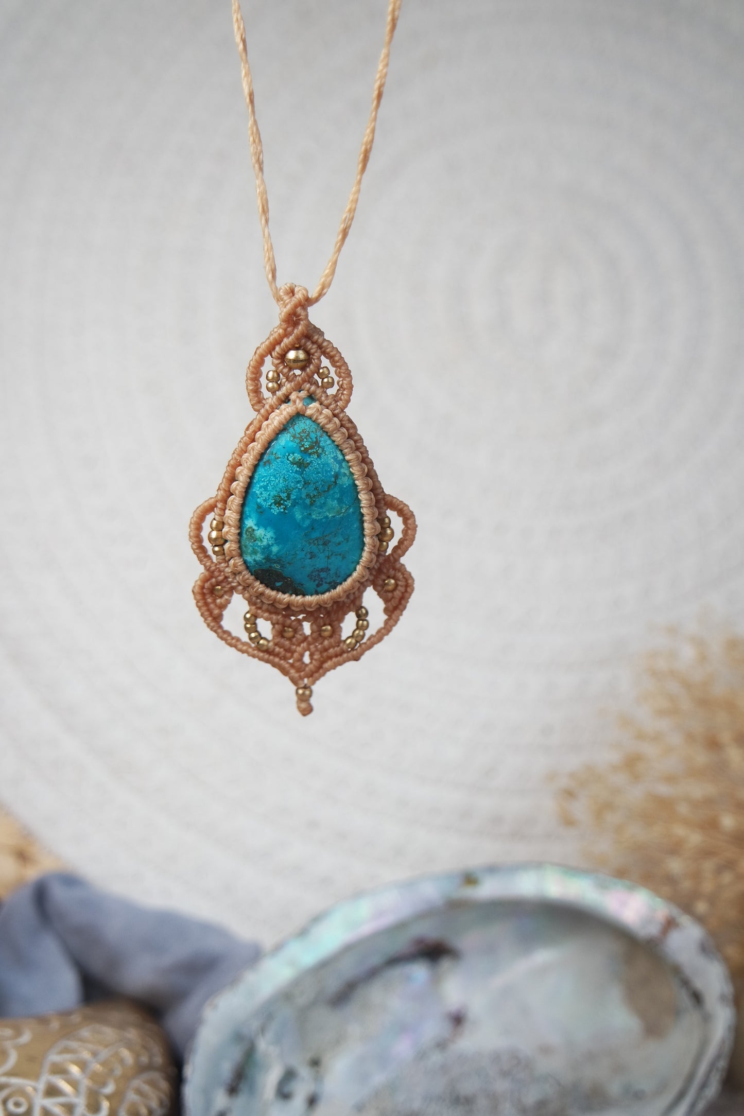 Handgeknüpfte Makramee Kette Strandseele mit blauem Chrysokoll und Messingperlen in sandfarbenem Makramee mit boho hintergrund.