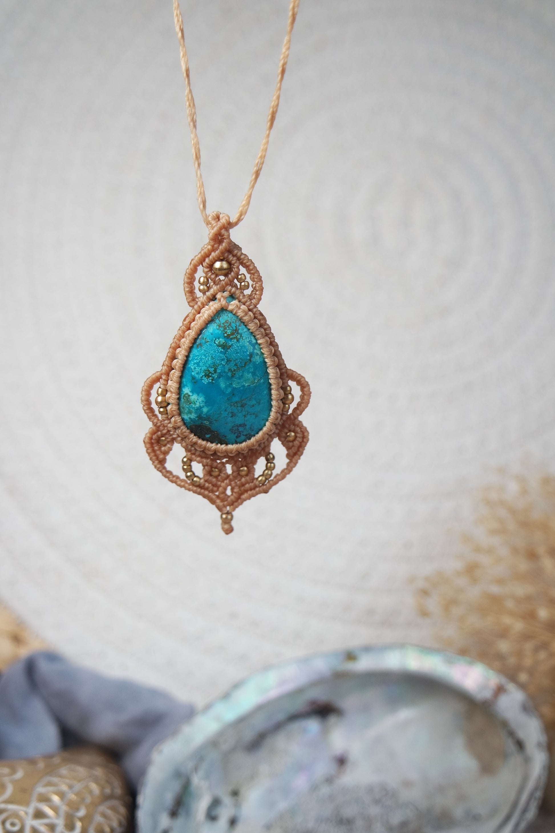 Handgeknüpfte Makramee Kette Strandseele mit blauem Chrysokoll und Messingperlen in sandfarbenem Makramee mit boho hintergrund.