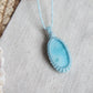 Larimar Kette in hellblauer Makrameefassung auf Leinenstoff.