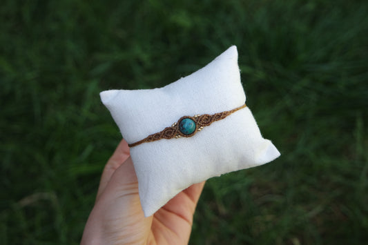 Makramee-Schmuck ‚Sonnenfunkeln‘ – filigranes Armband mit Türkisstein und Messingperlen auf heller Stoffunterlage präsentiert