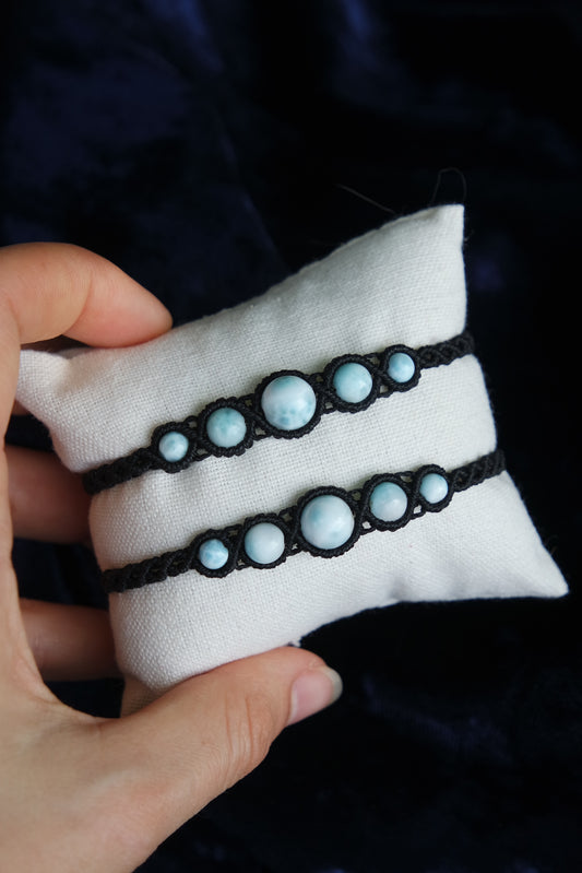 Makramee-Armband „Morgenwelle“ mit mehreren Larimar-Perlen auf hellem Kissen.

