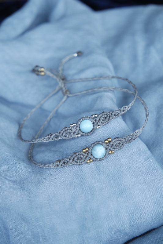 Minimalistisches Schmuckstück mit Larimar-Stein auf blauer Stoffstruktur.

